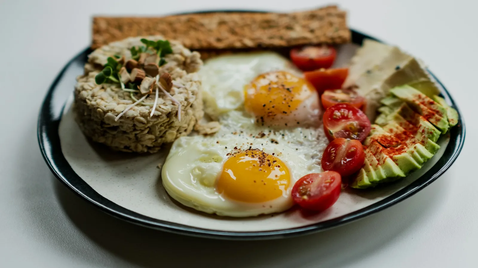 Brødskive med egg og grønnsaker på en hvit tallerken